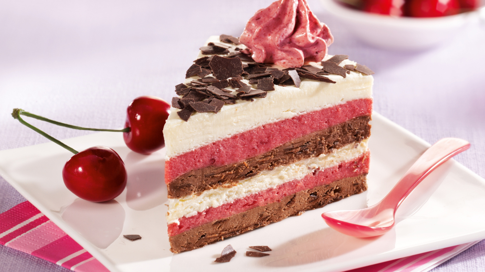 Кусок торта с вишневым и шоколадным кремом на белой тарелке