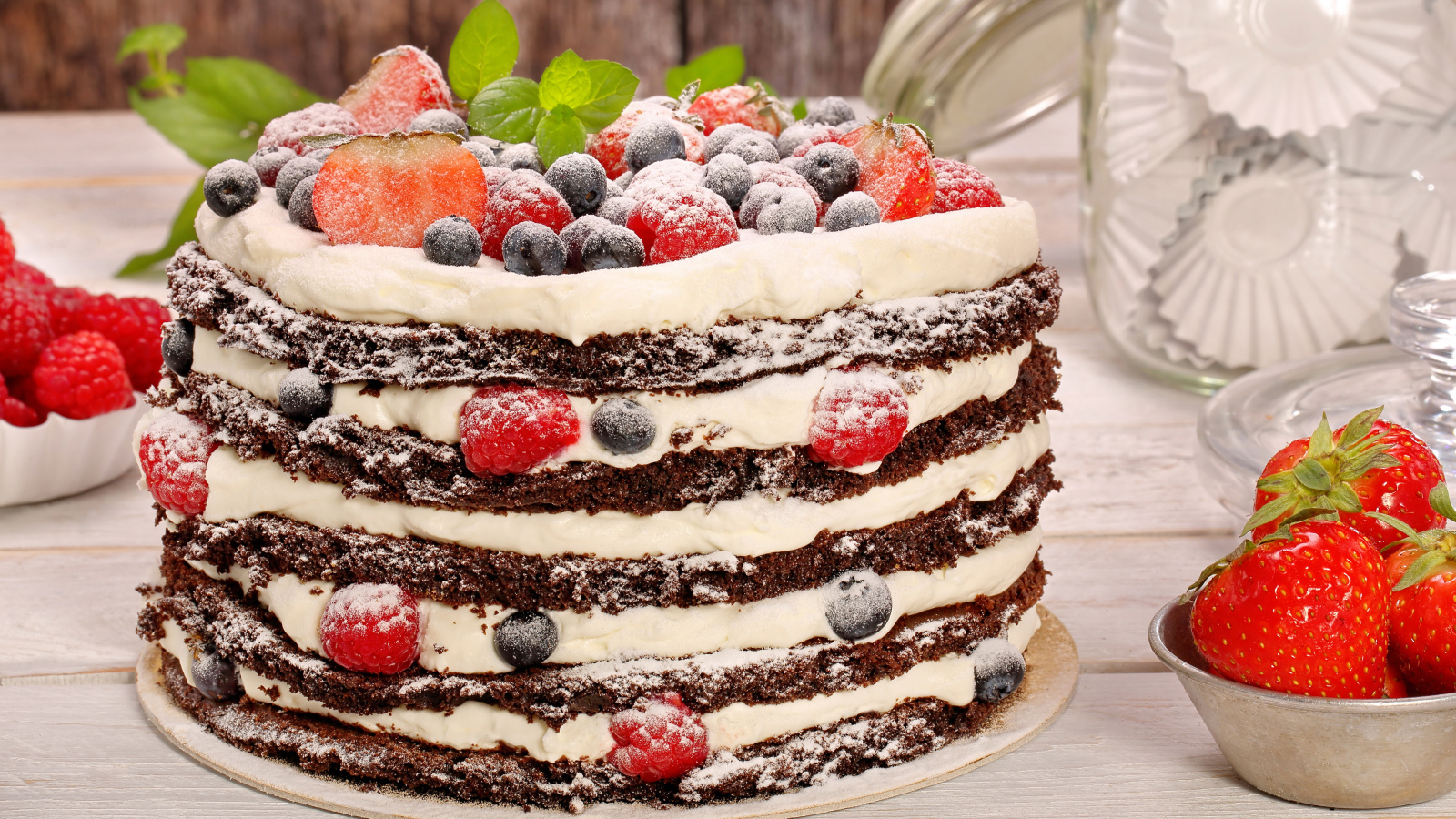 Аппетитный торт с кремом и ягодами посыпан сахарной пудрой