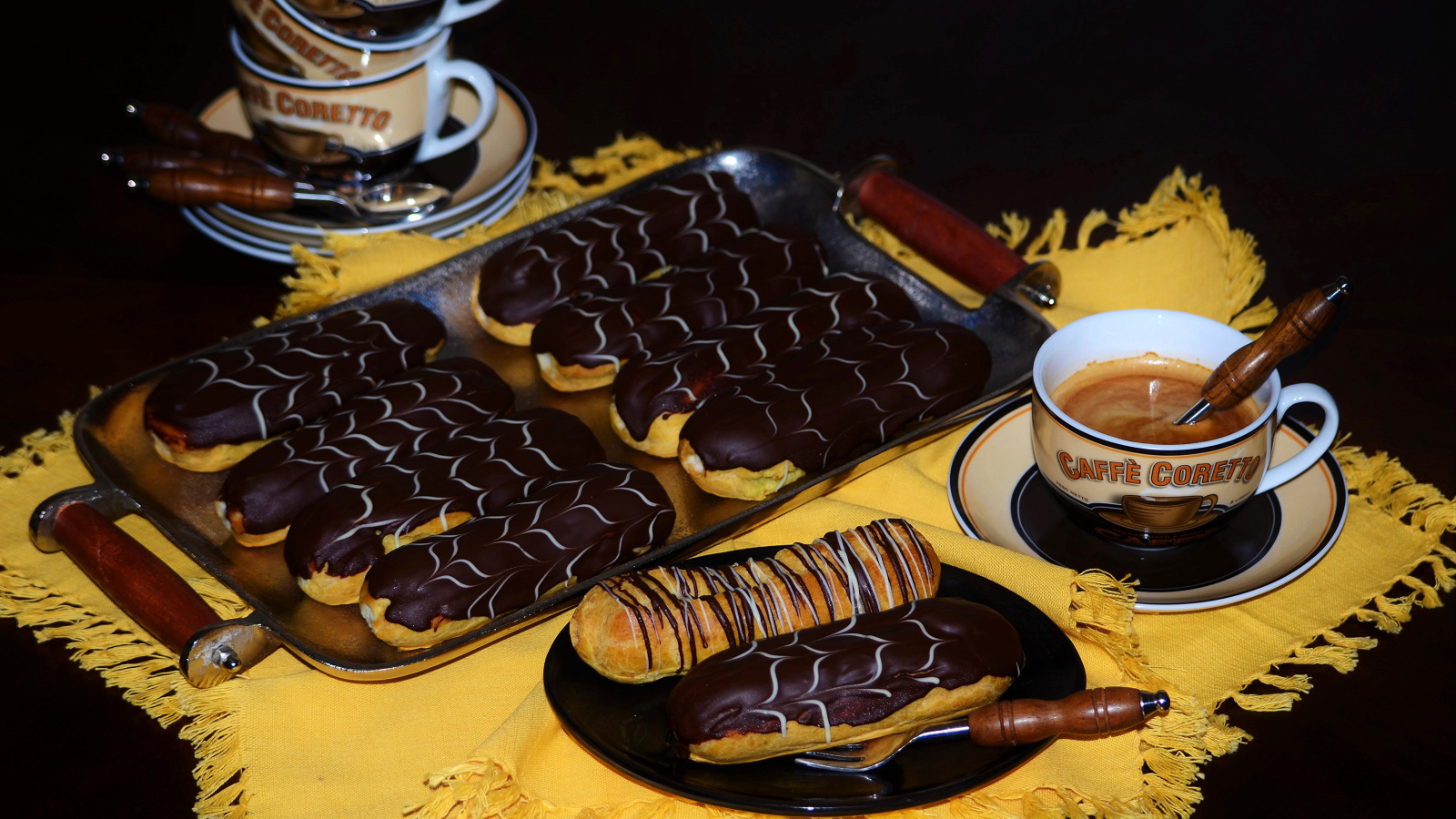Аппетитные сладкие эклеры с шоколадом и чашками кофе на столе