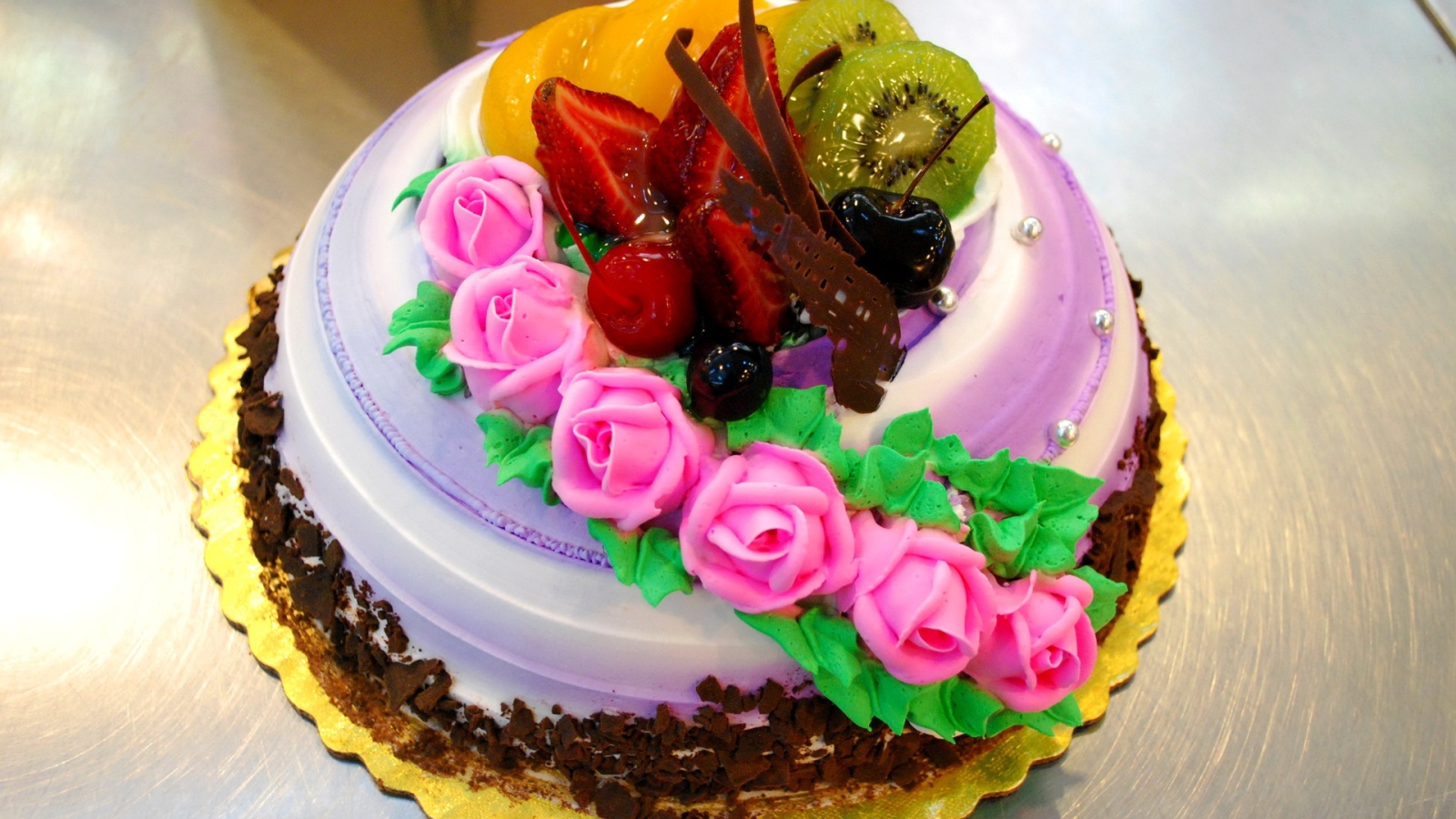 Красивый торт с фруктами украшен розовыми розами из крема