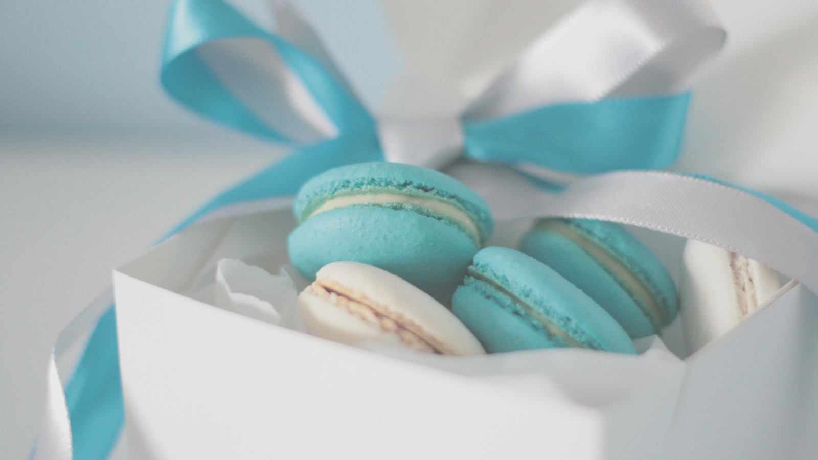 Голубые макаруны в белой коробке с белой и голубой лентой