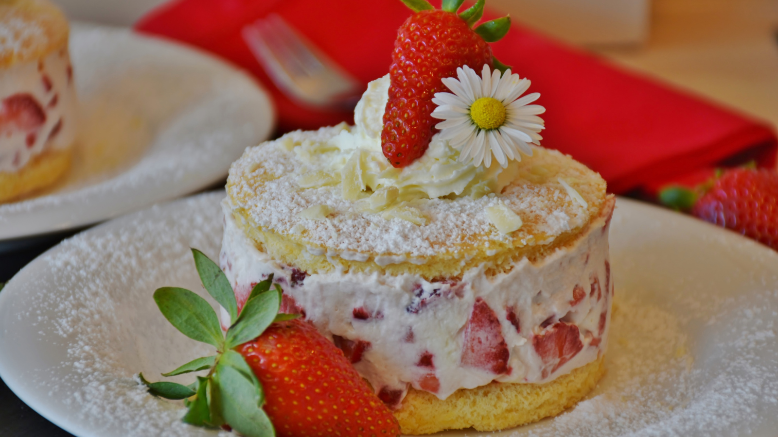 Торт со сливочным кремом и свежими ягодами клубники на белой тарелке