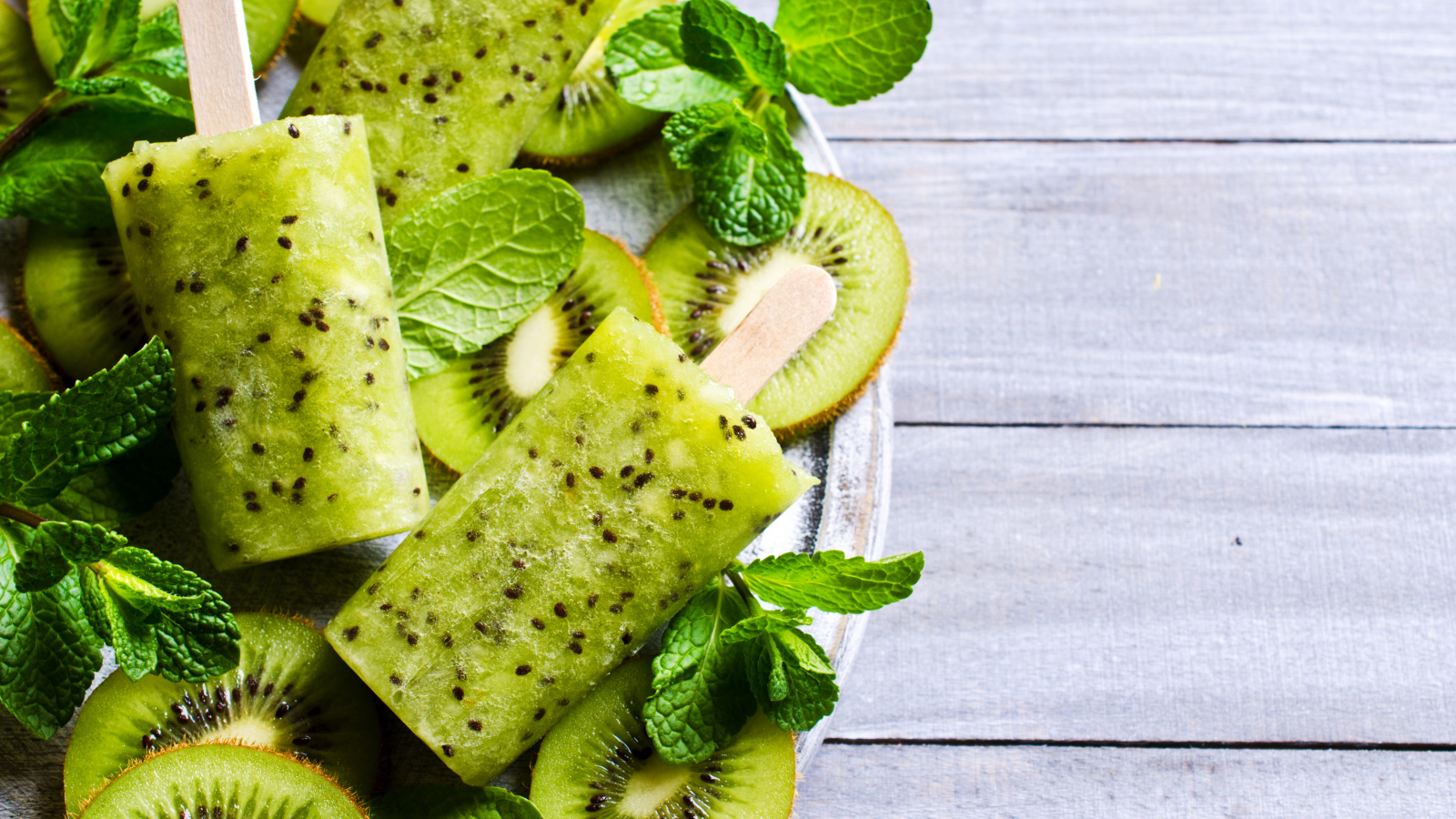 Мороженое с киви и листиками мяты на деревянном столе