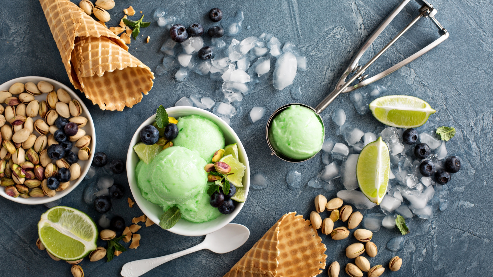 Мороженое с лаймом и фисташками на столе с вафельными рожками и льдом