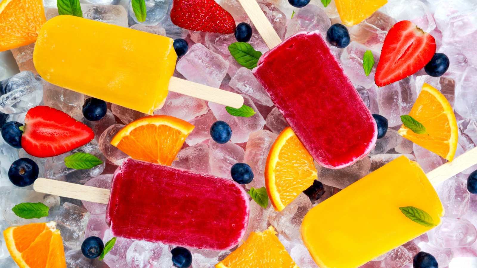 Разноцветное фруктовое мороженое с ягодами лежит на кусочках льда