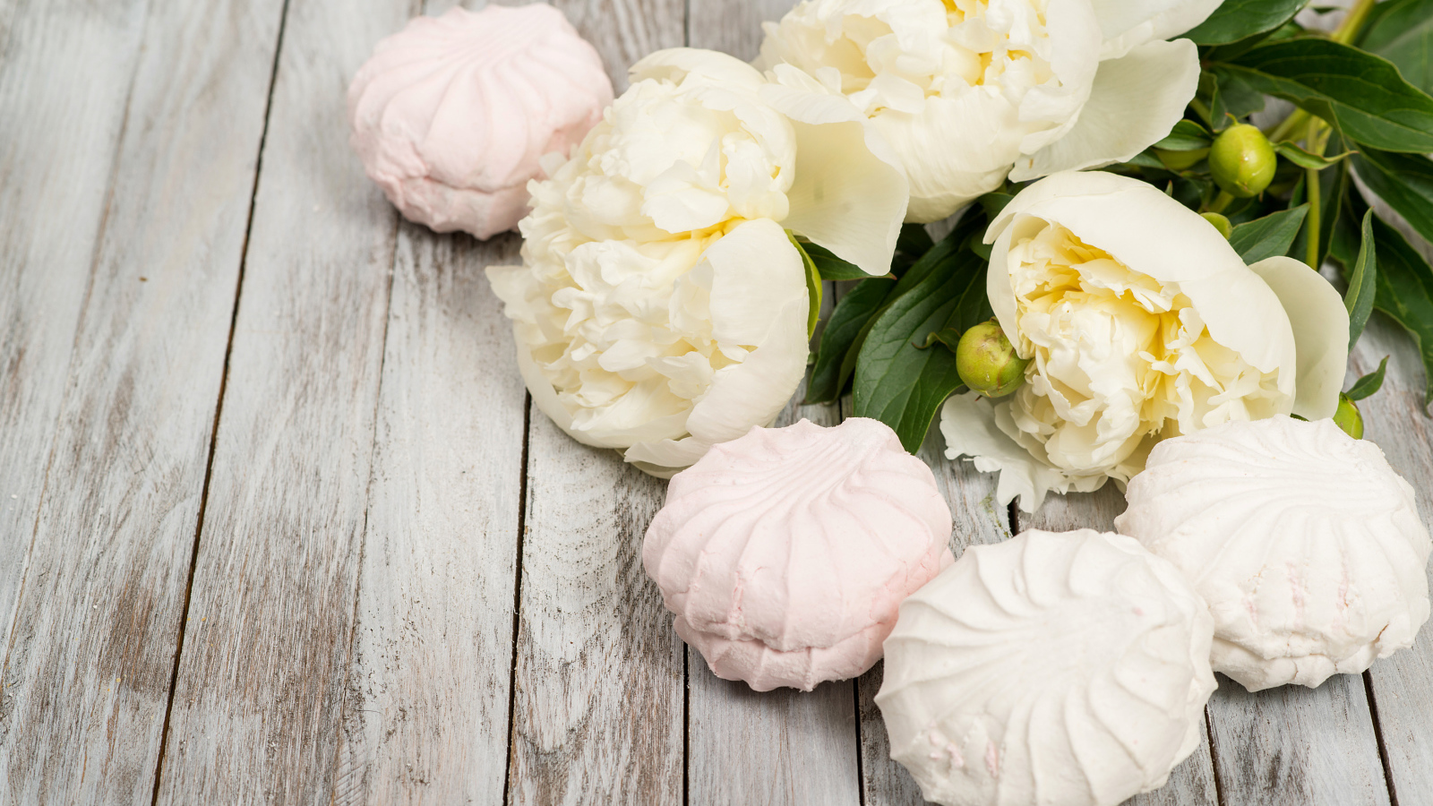 Сладкий зефир на столе с белыми пионами