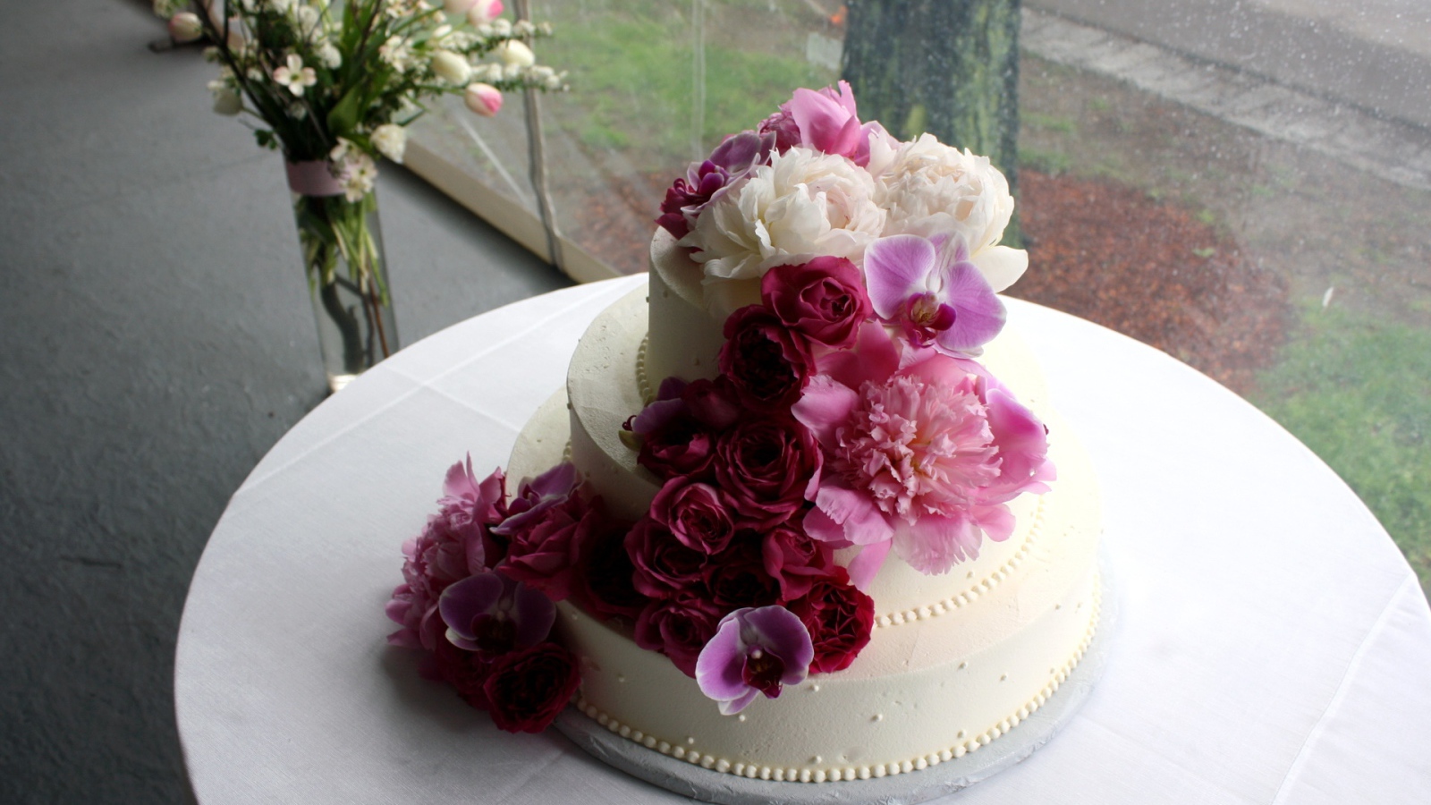 Большой свадебный торт украшен живыми цветами