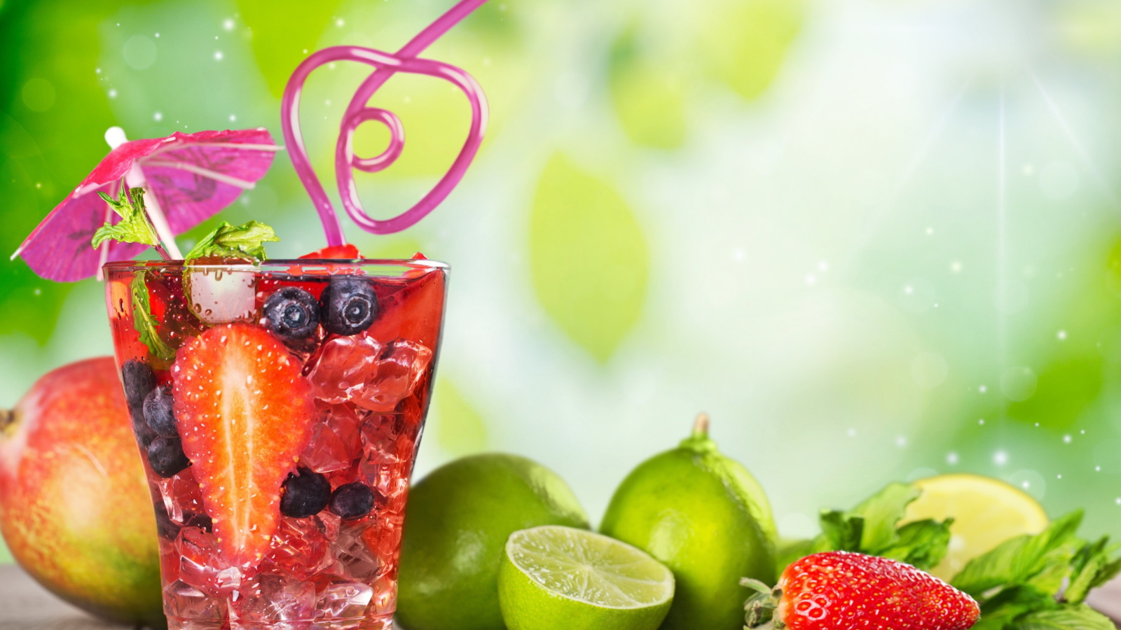 Коктейль с клубникой и ягодами черники в стакане со льдом на столе с лаймами и клубникой