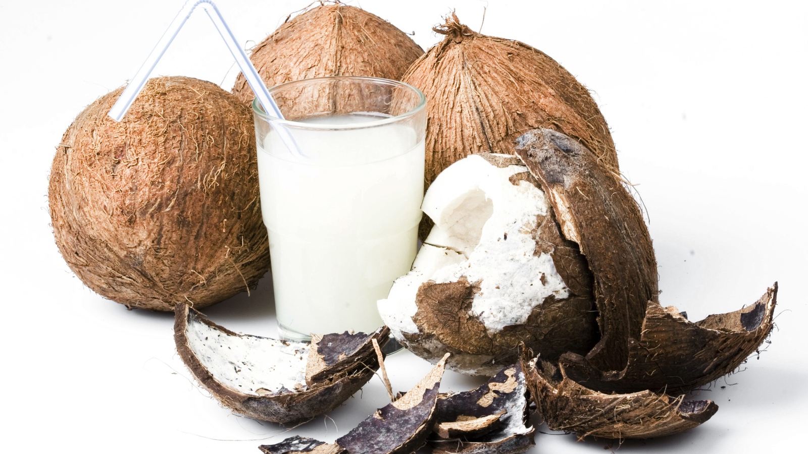 Кокосовое молоко в стакане и кокосы на белом фоне