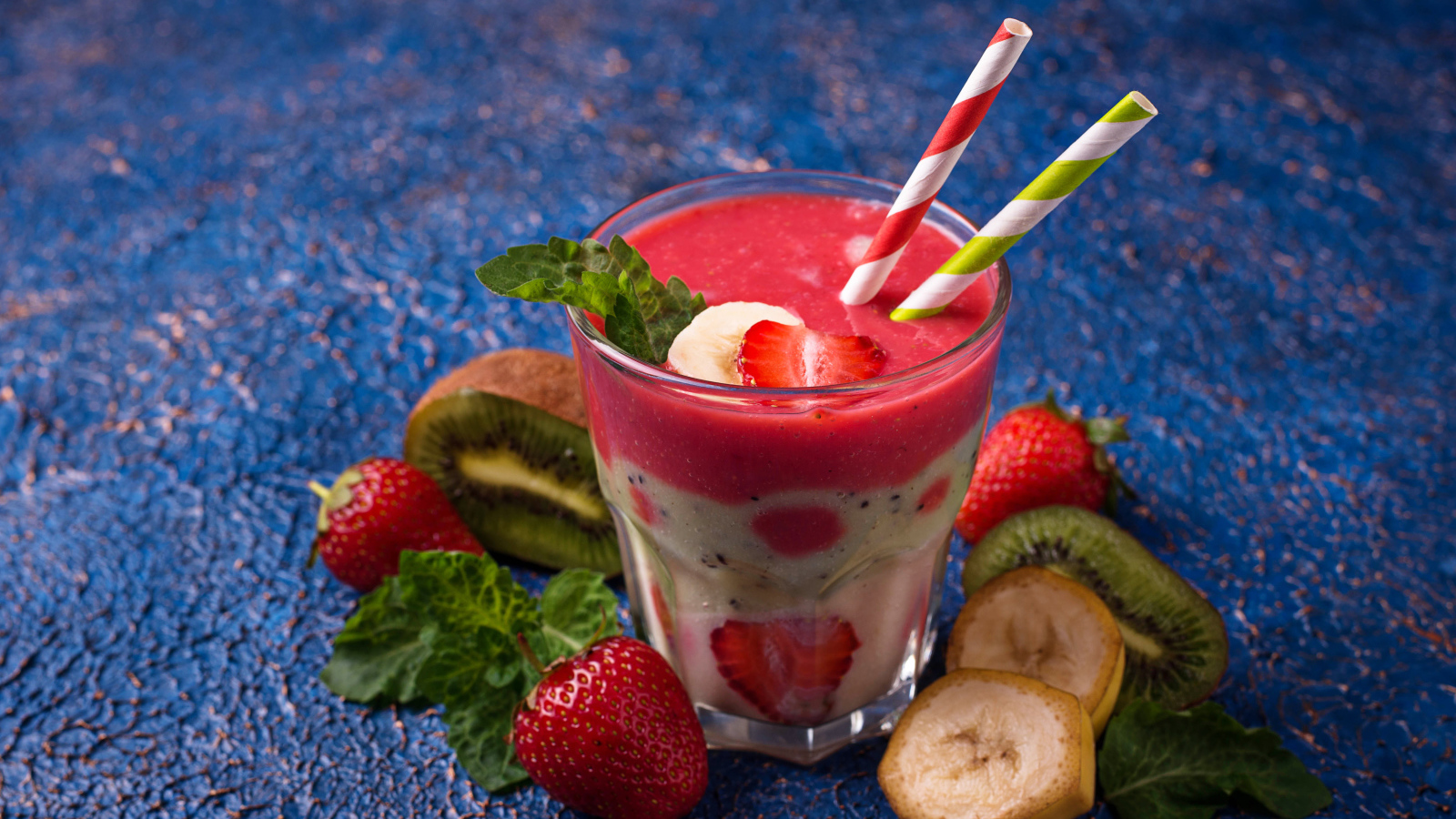 Фруктовый коктейль с клубникой, бананом и киви в стакане с трубочками