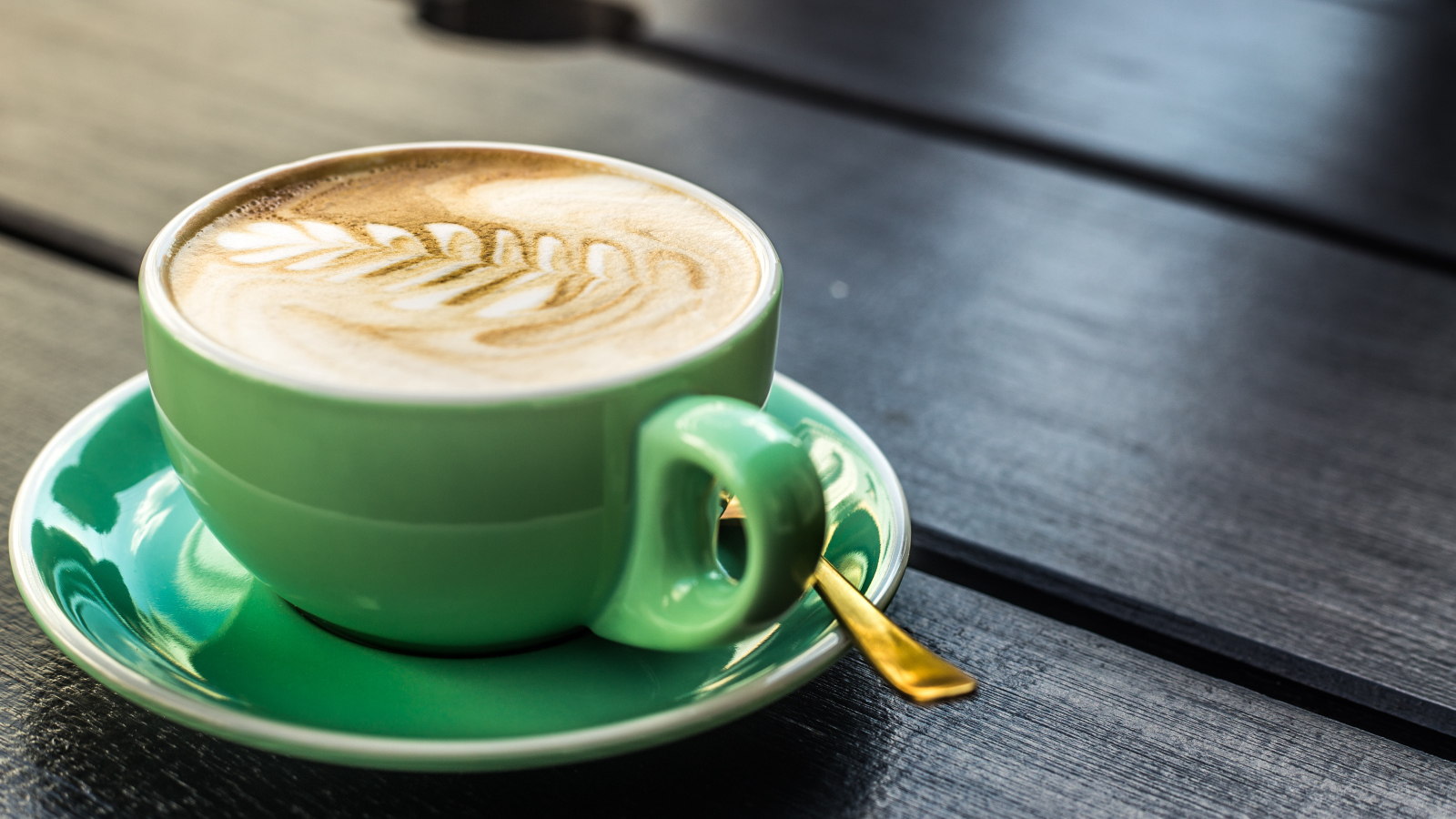 Зеленая чашка капучино с белой пенкой 