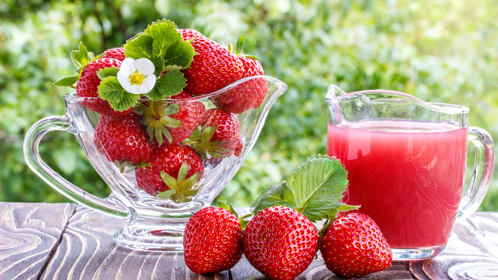 Клубничный сок в стеклянном графине на столе со свежей клубникой