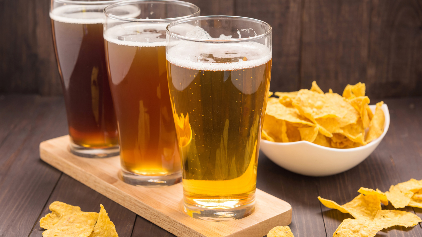 Три стакана пива на столе с чипсами