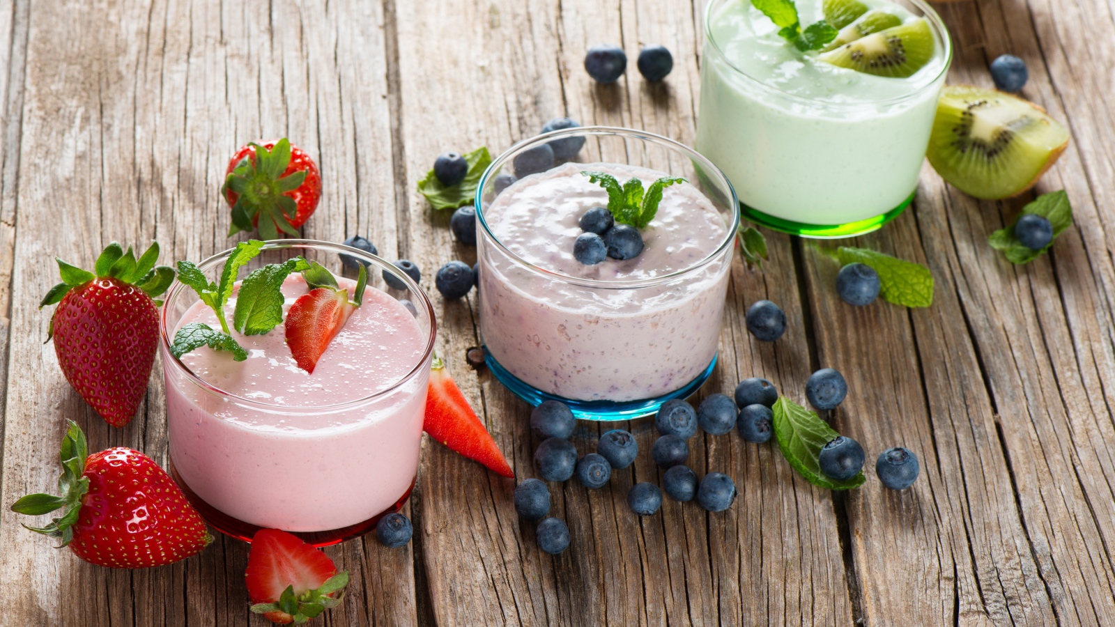 Три стакана смузи с клубникой, киви и черникой и свежими ягодами