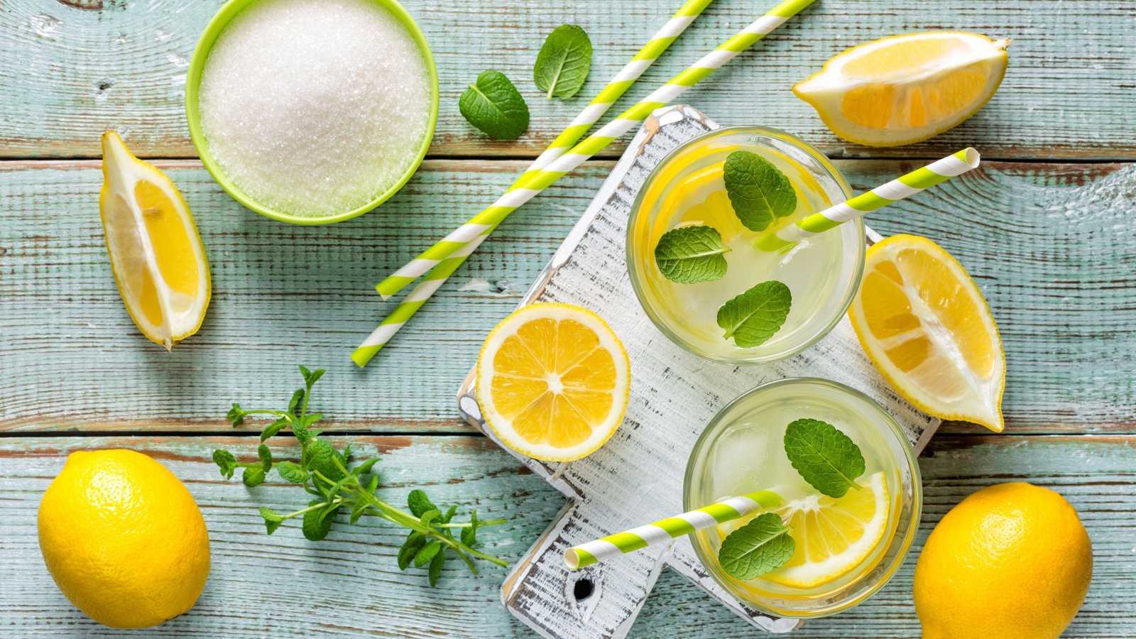 Два стакана с лимонадом, мятой, свежими лимонами и сахаром на столе