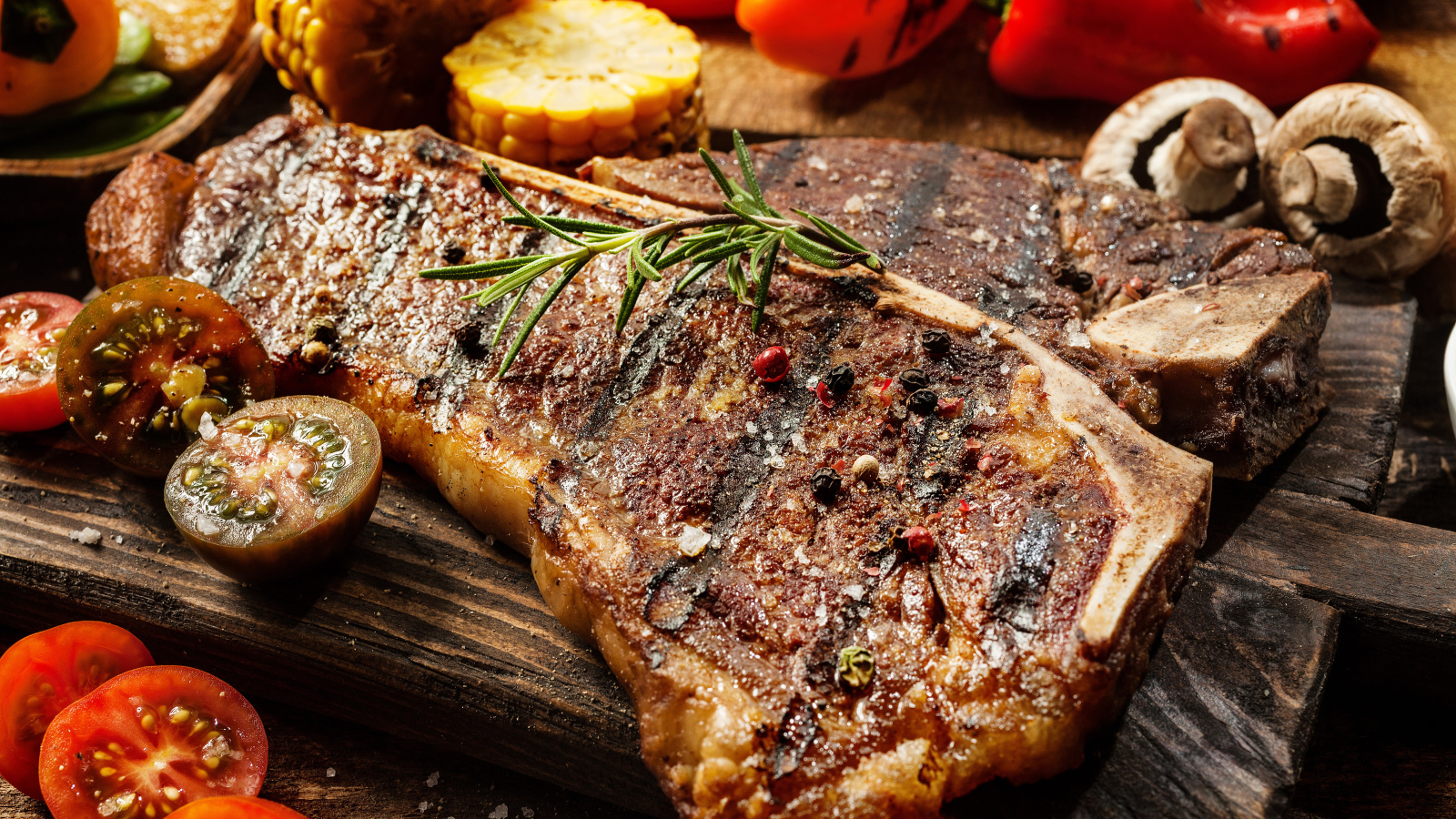 Кусок сочного жареного мяса на разделочной доске с овощами