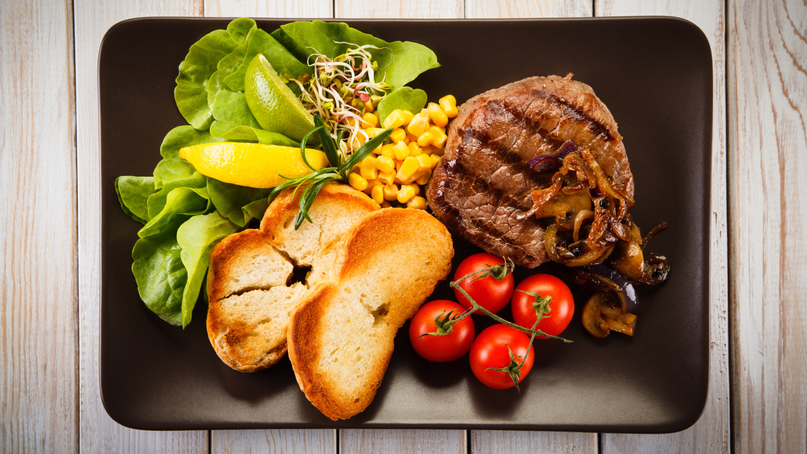 Аппетитный кусок жареного мяса на тарелке с овощами и гренками