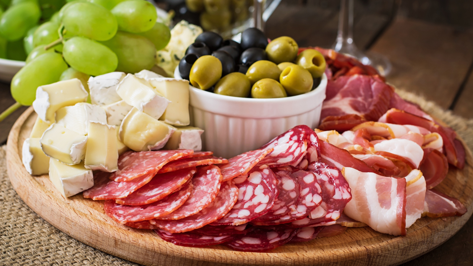 Мясная нарезка с сыром и оливками на разделочной доске