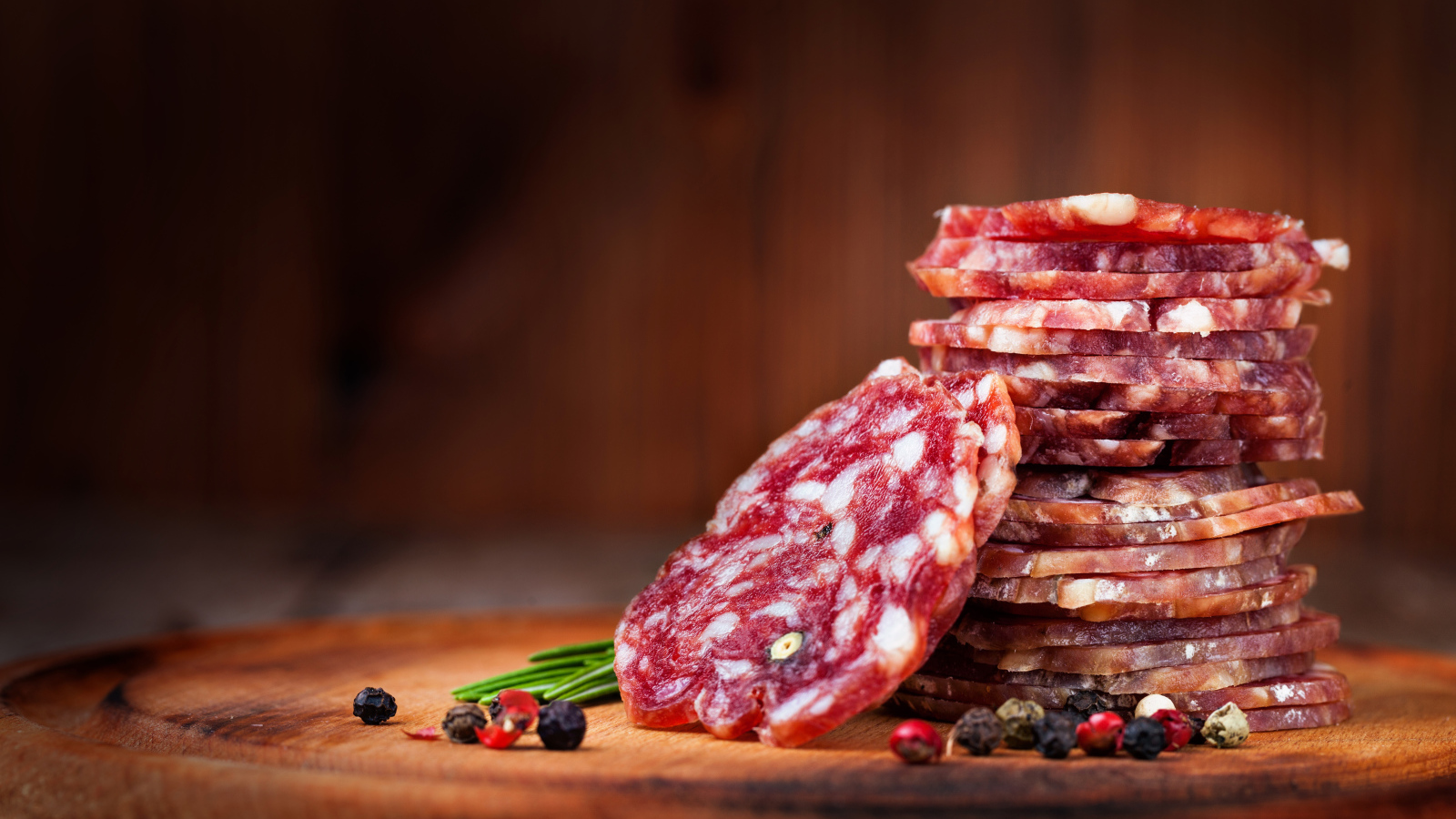 Нарезанная сухая колбаса на столе со специями