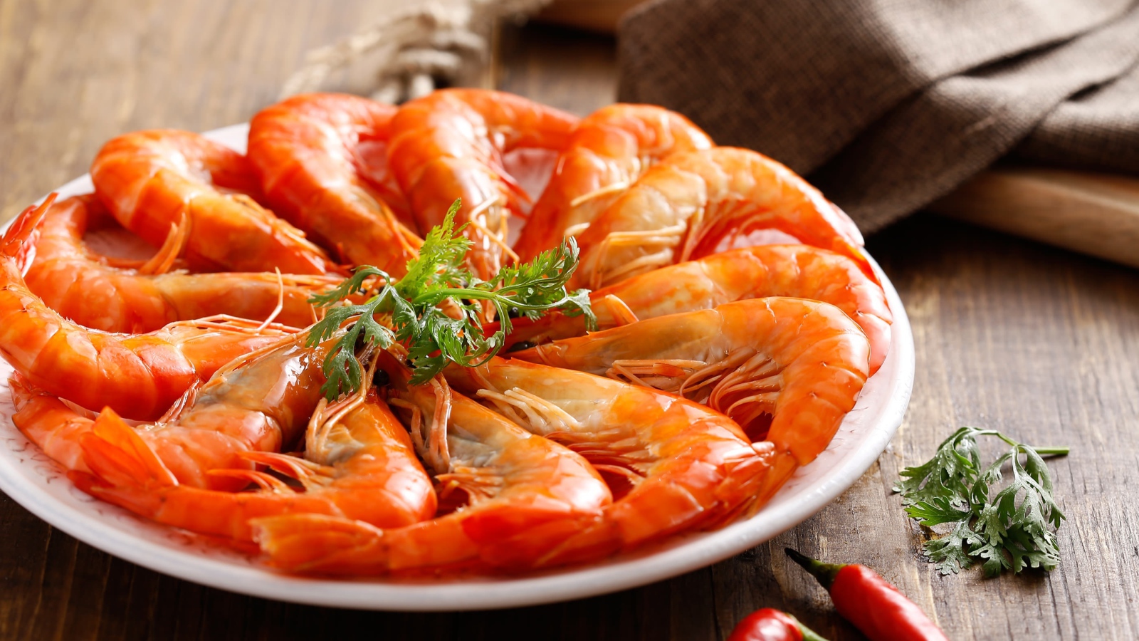 Аппетитные вареные креветки на тарелке с зеленью петрушки