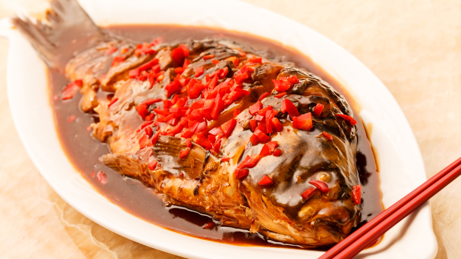 Жареная рыба с соусом и красным перцем в белом блюде