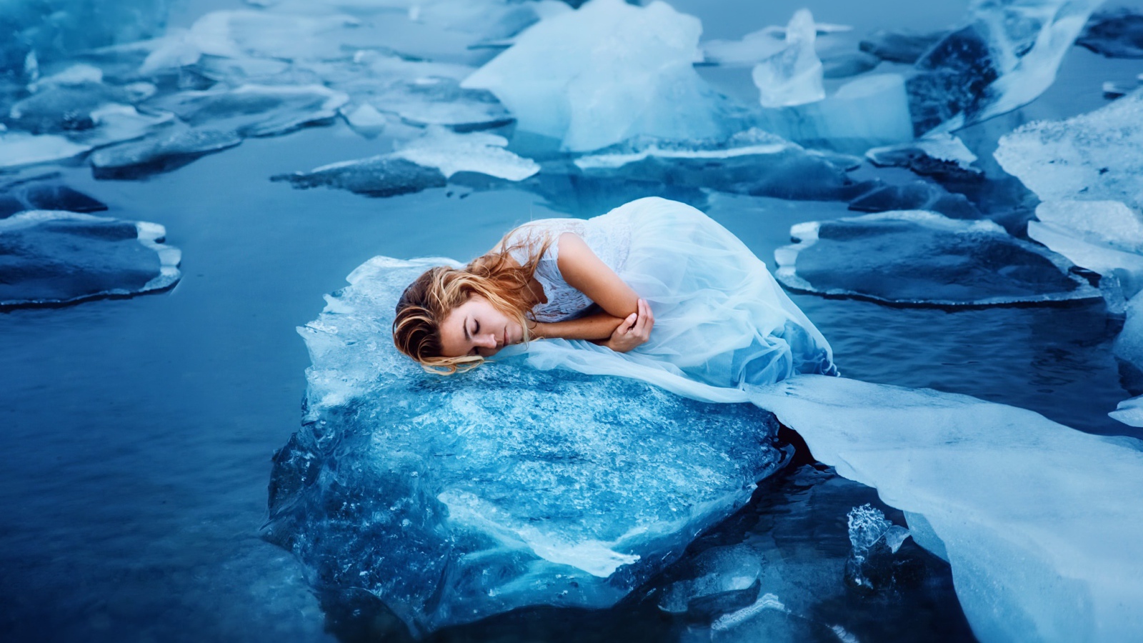 Девушка в красивом белом платье лежит на льдине