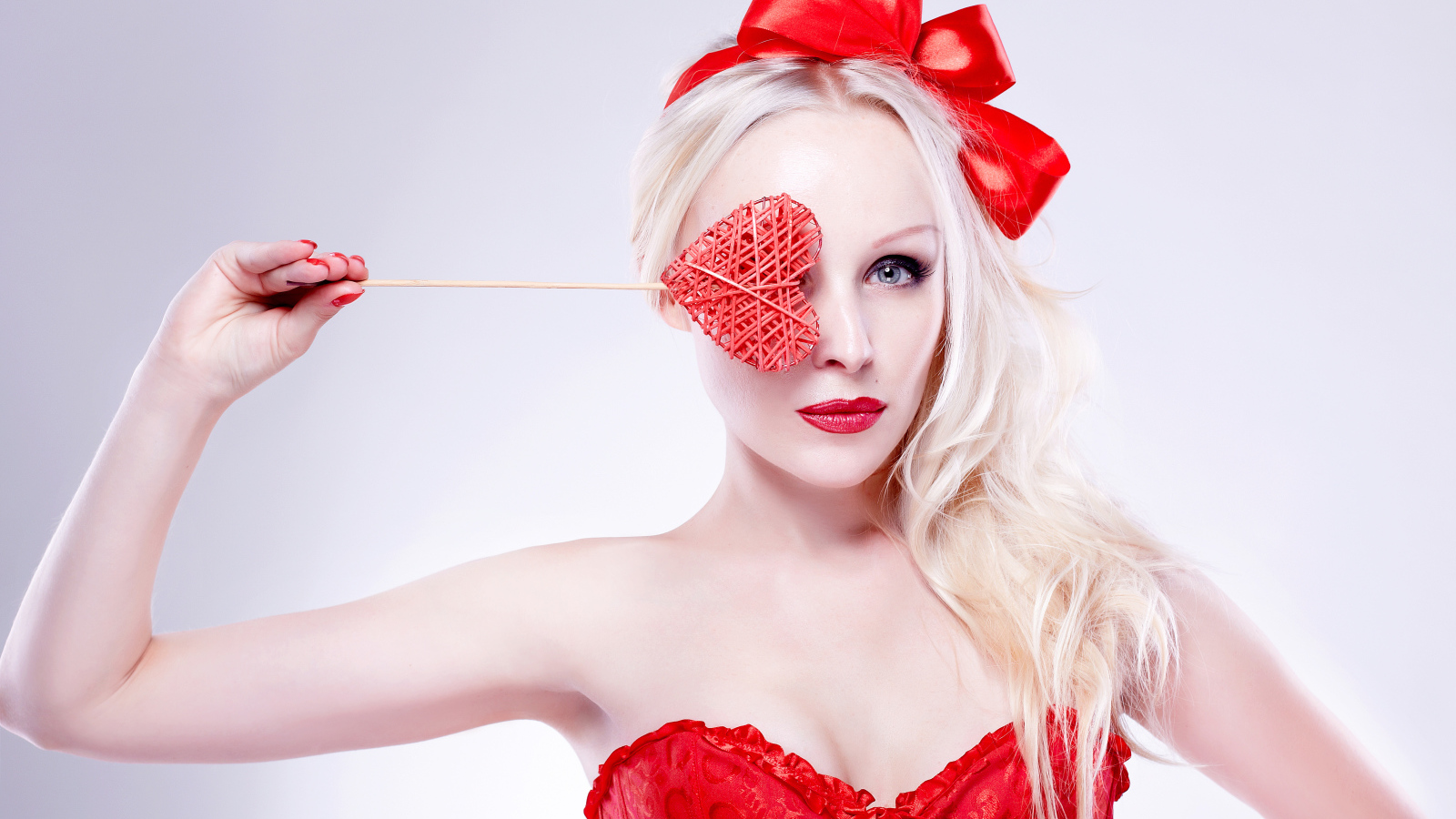 Красивая девушка блондинка в красном наряде с сердечком в руке