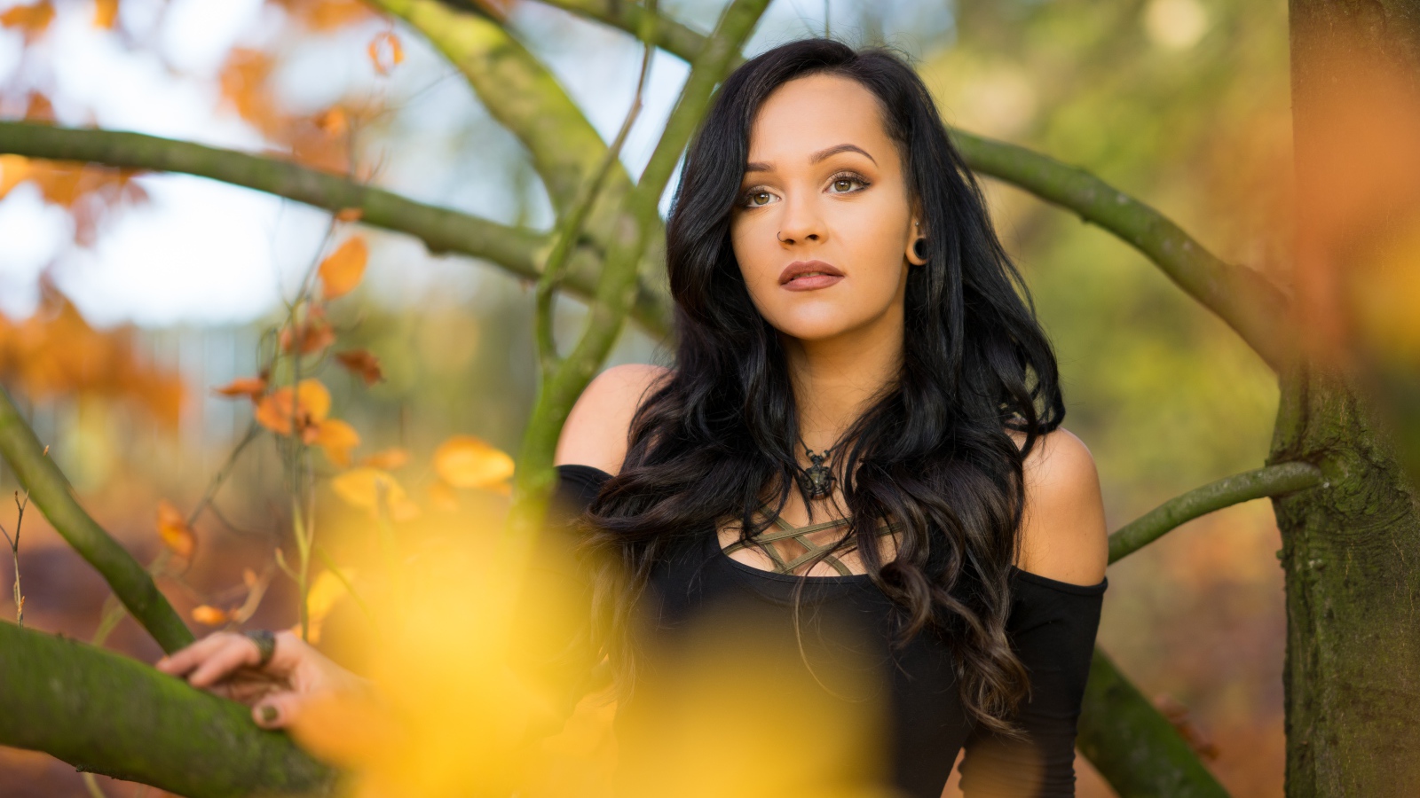 Красивая брюнетка у дерева в черном платье