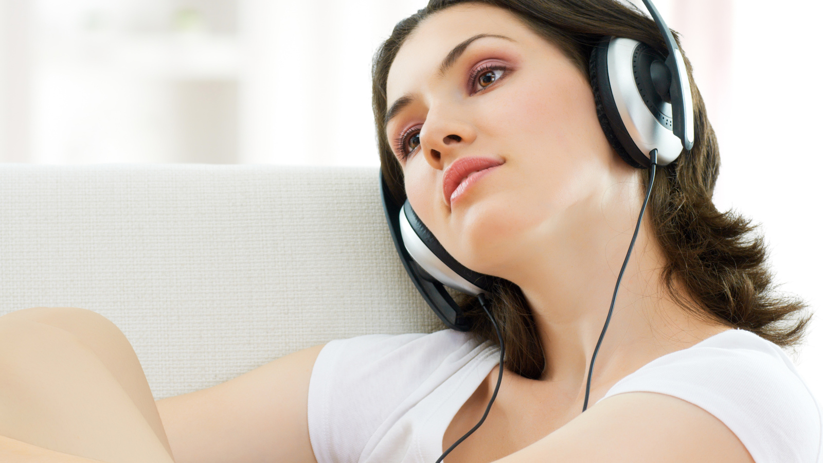 Красивая нежная шатенка слушает музыку в наушниках