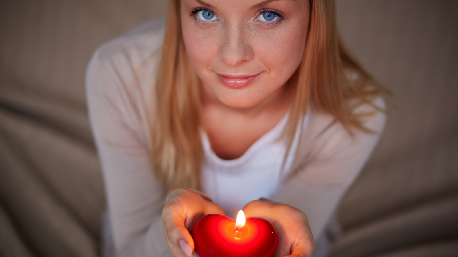 Красивая девушка держит в руках свечу в форме сердца