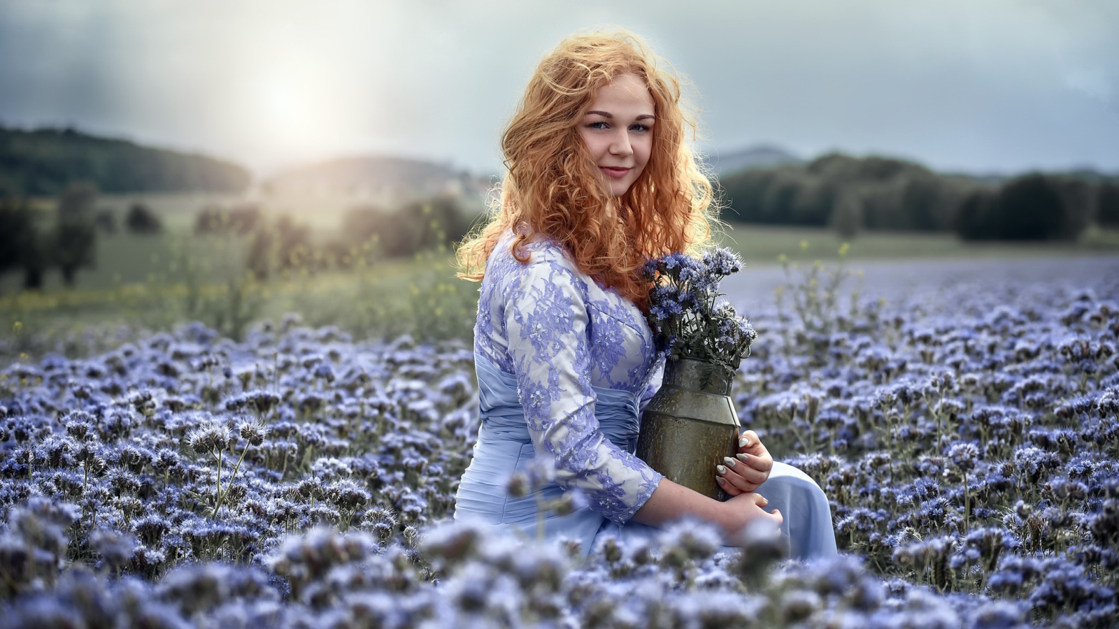 Красивая рыжеволосая девушка собирает цветы