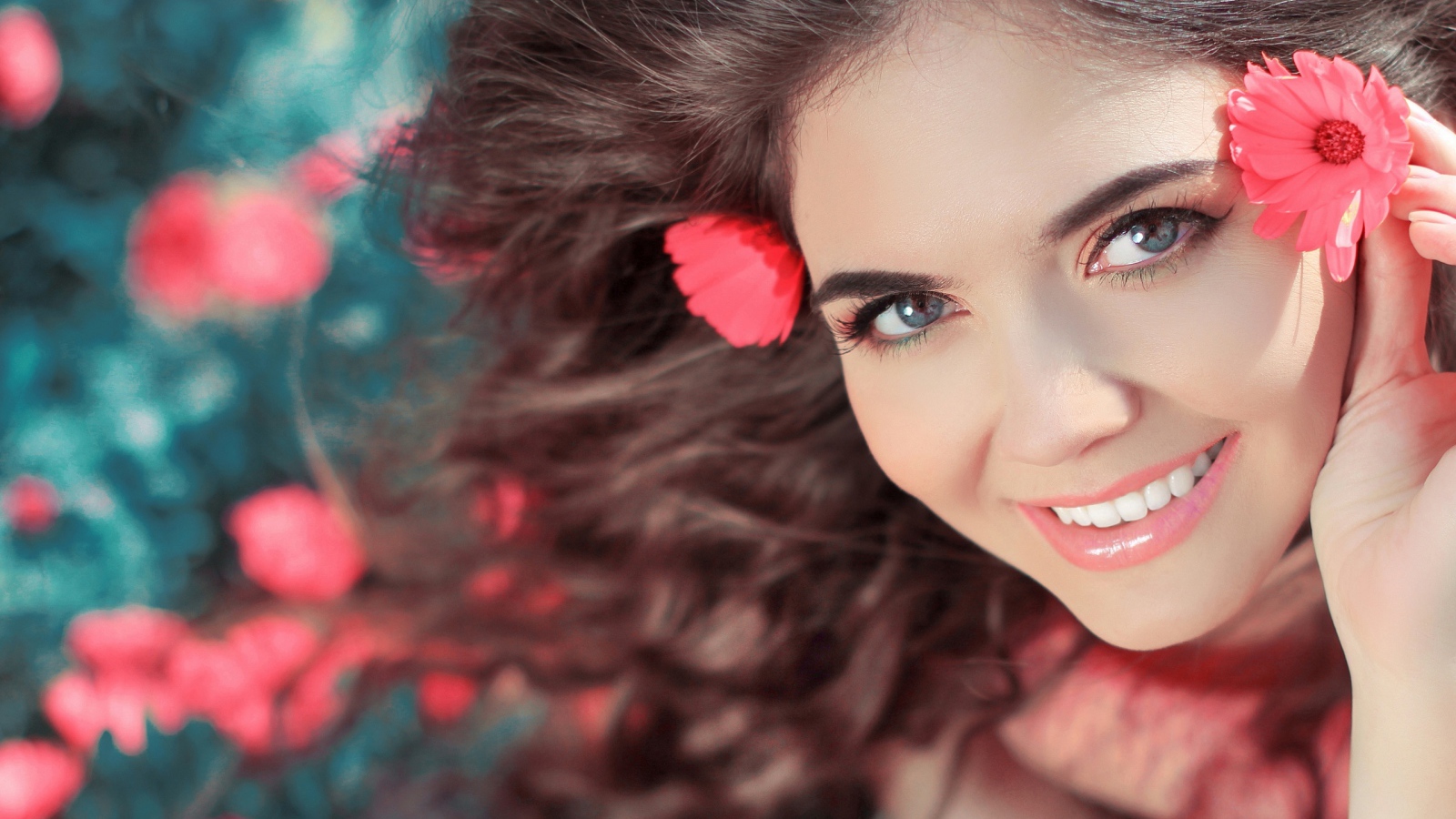 Красивая улыбающаяся девушка с розовыми цветами в волосах 