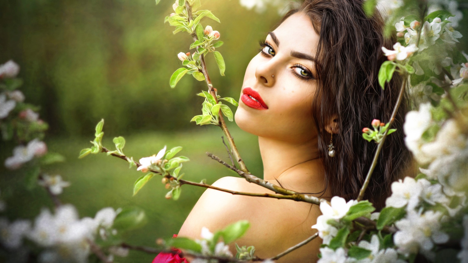 Красивая молодая девушка в ветках цветущей яблони 