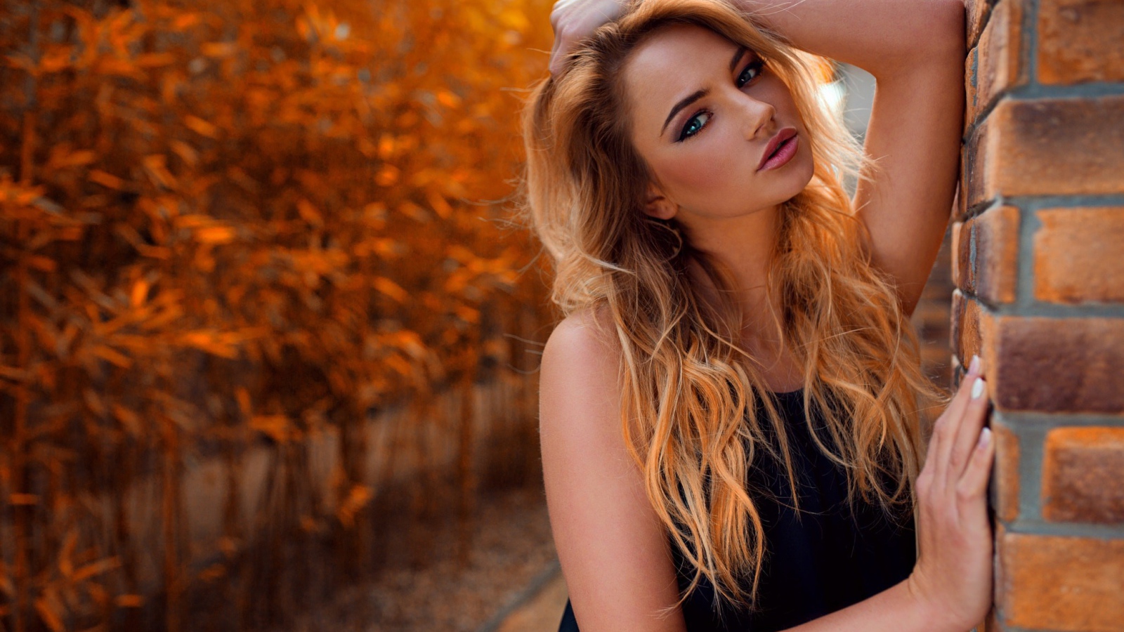 Голубоглазая девушка блондинка у стены 