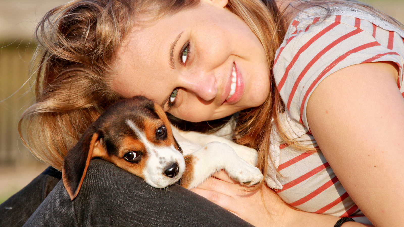 Убающаяся девушка шатенка с милым щенком на руках