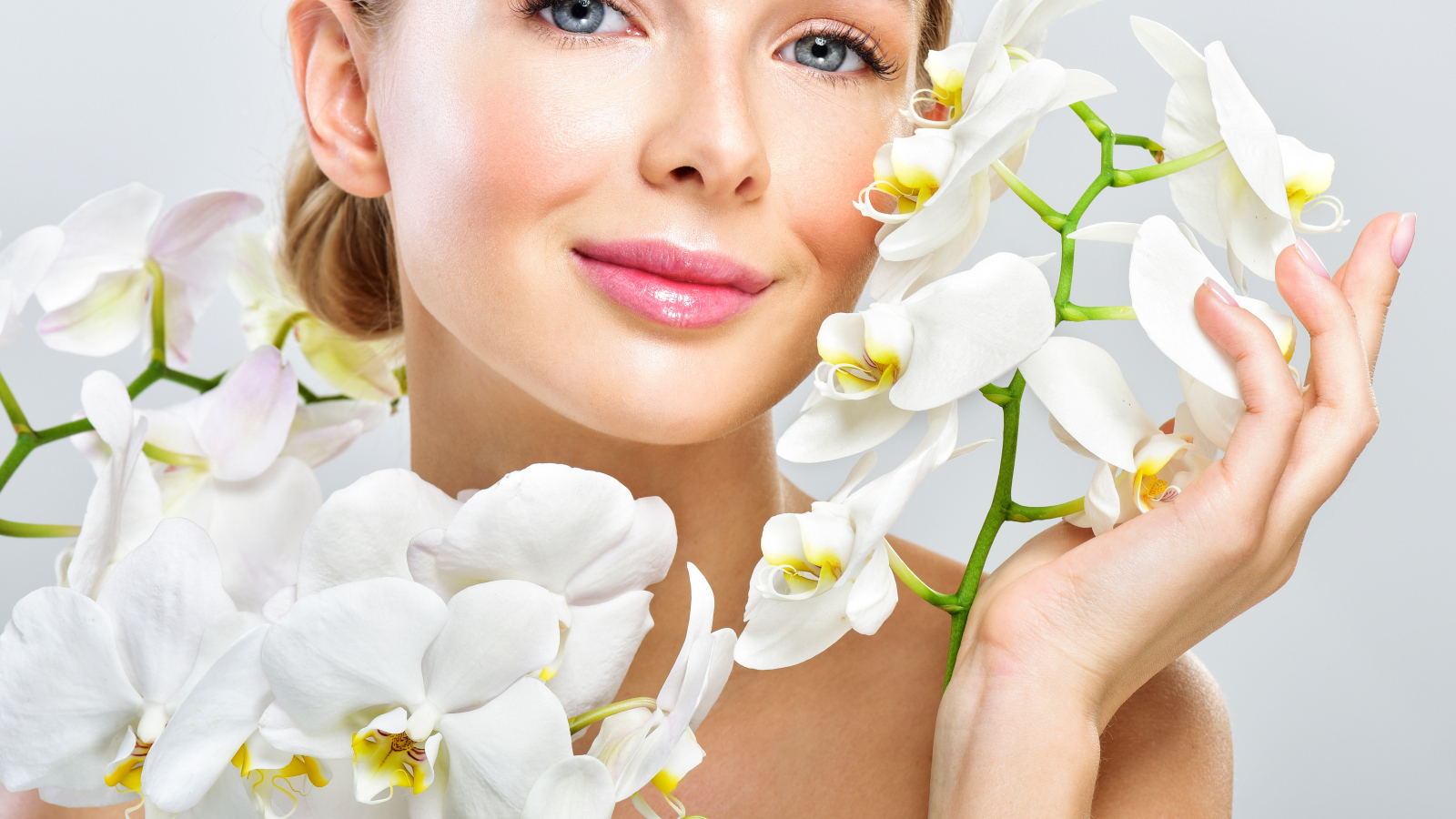 Нежная голубоглазая девушка с цветами орхидеи в руках