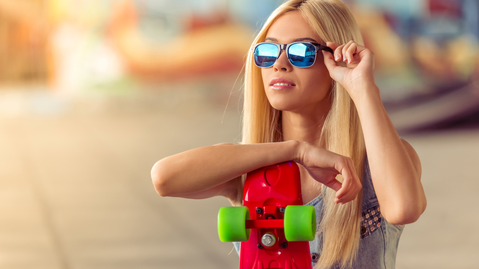 Молодая блондинка в солнечный очках со скейтбордом