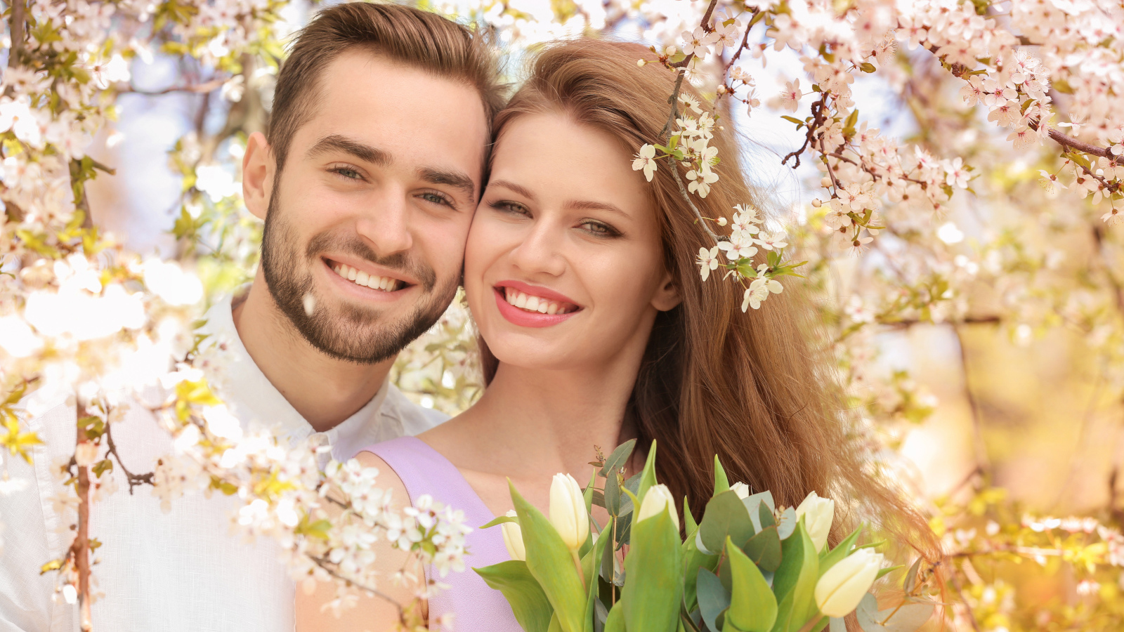 Улыбающаяся влюбленная пара у цветущего дерева