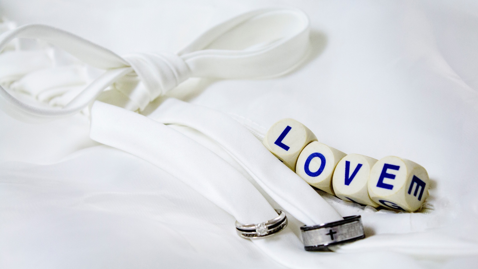 Два кольца перевязанные белой лентой и кубики с надписью любовь