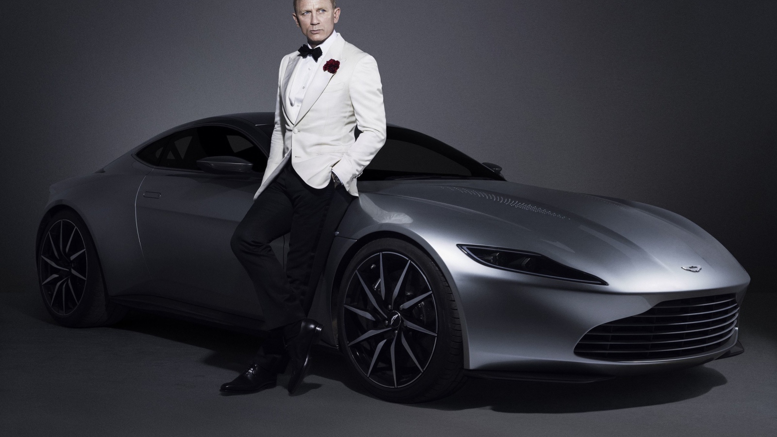 Знаменитый актер Дэниел Крэйг рядом с серебристым автомобилем Aston Martin