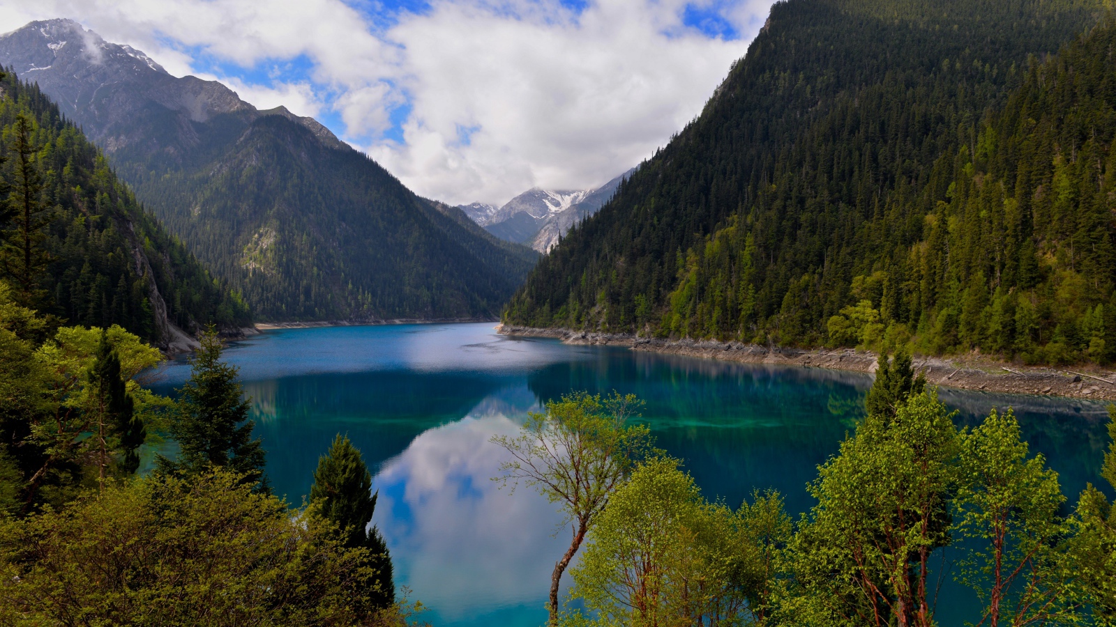 Красивое озеро у покрытых лесом гор в парке Цзючжайгоу, Китай