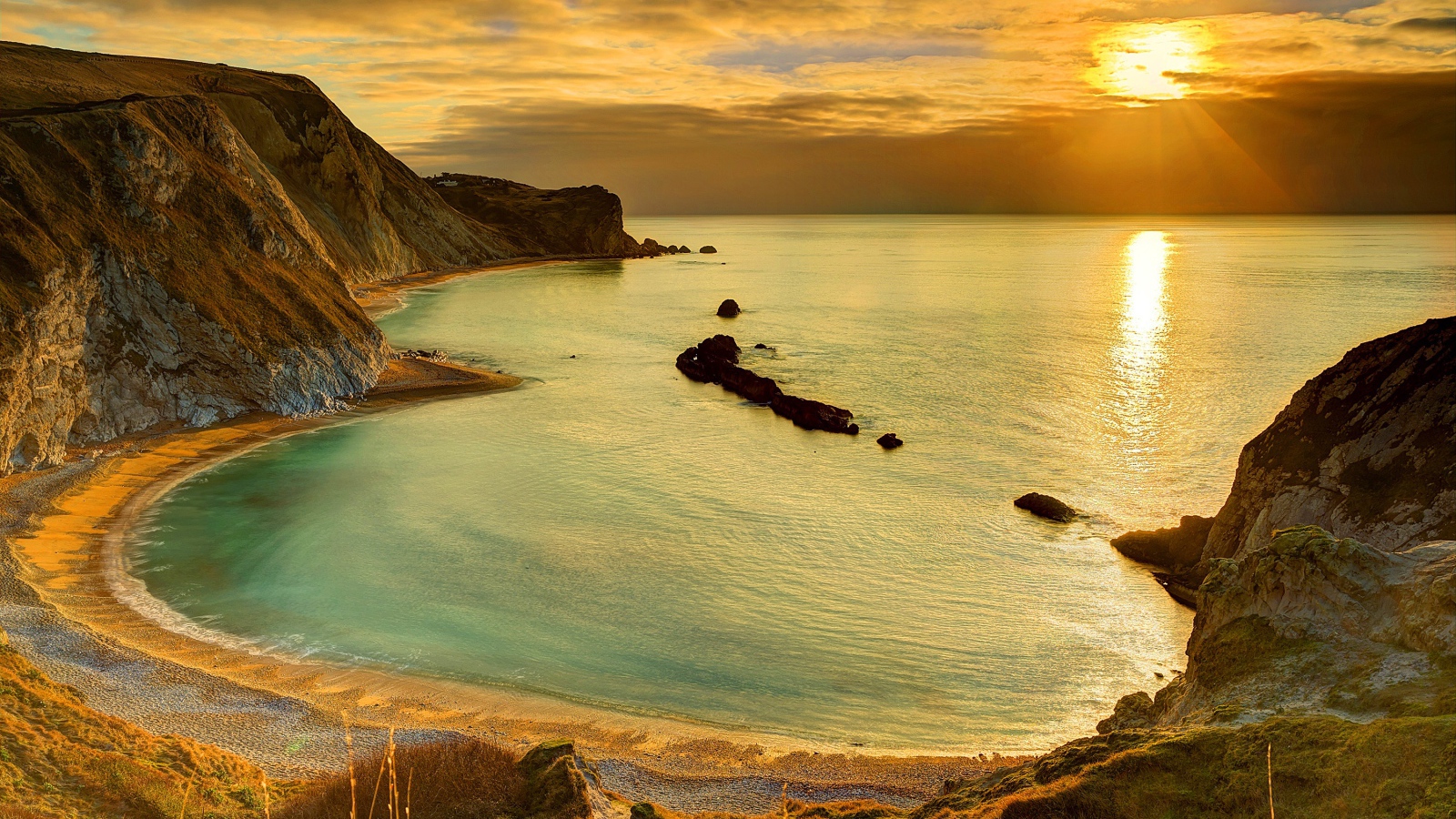 Скалы на берегу океана в лучах солнца на закате