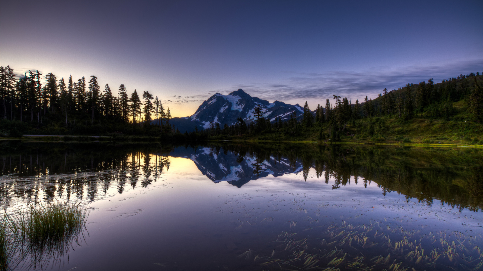 Заснеженная гора и лес отражается в озере вечером