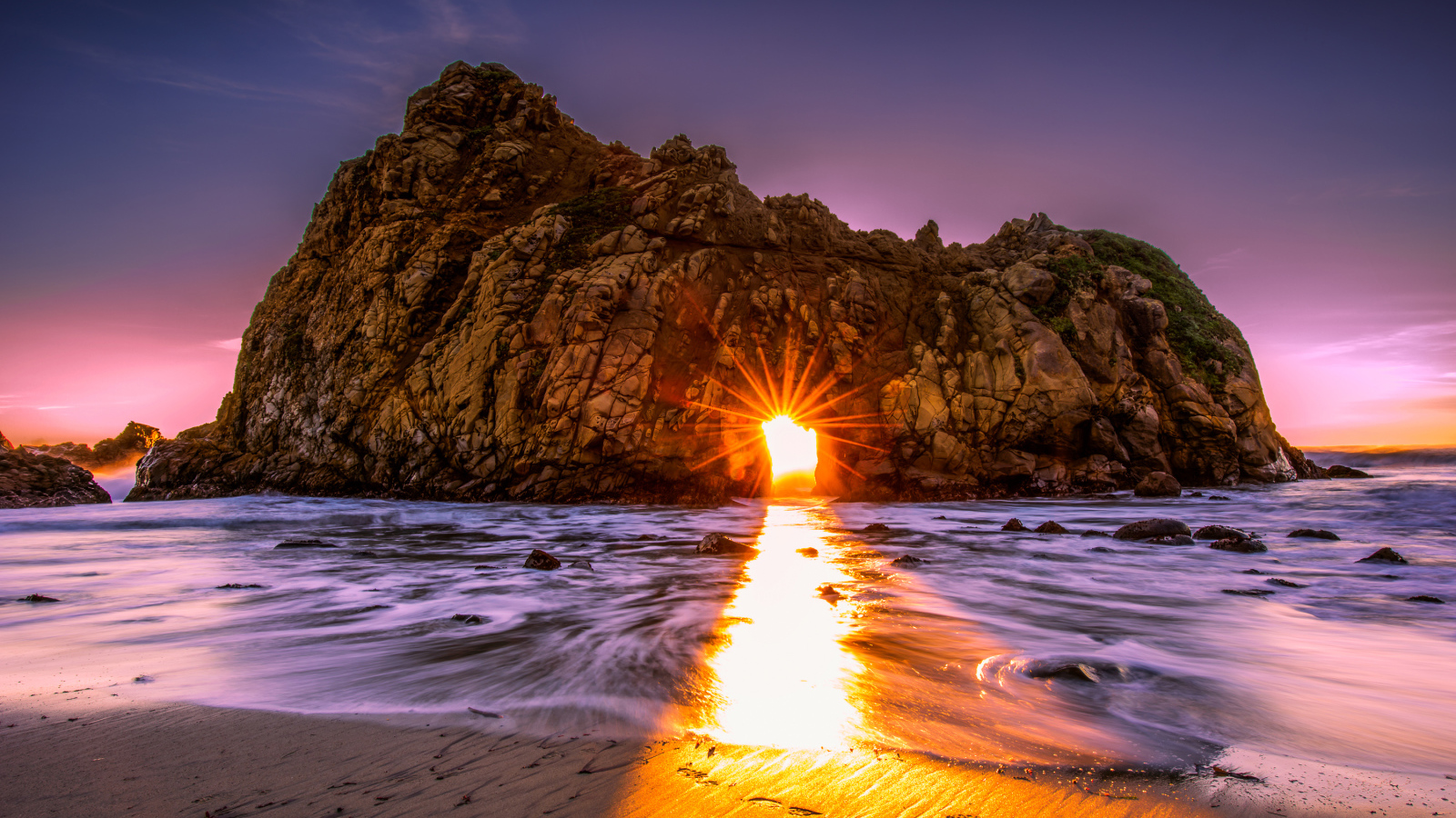 Лучи солнца пробиваются сквозь отверстие в скале  Pfeiffer Beach Big Sur, Калифорния  
