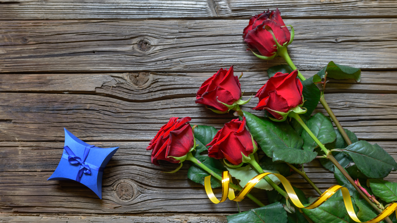 Букет красных роз на столе с синей коробочкой