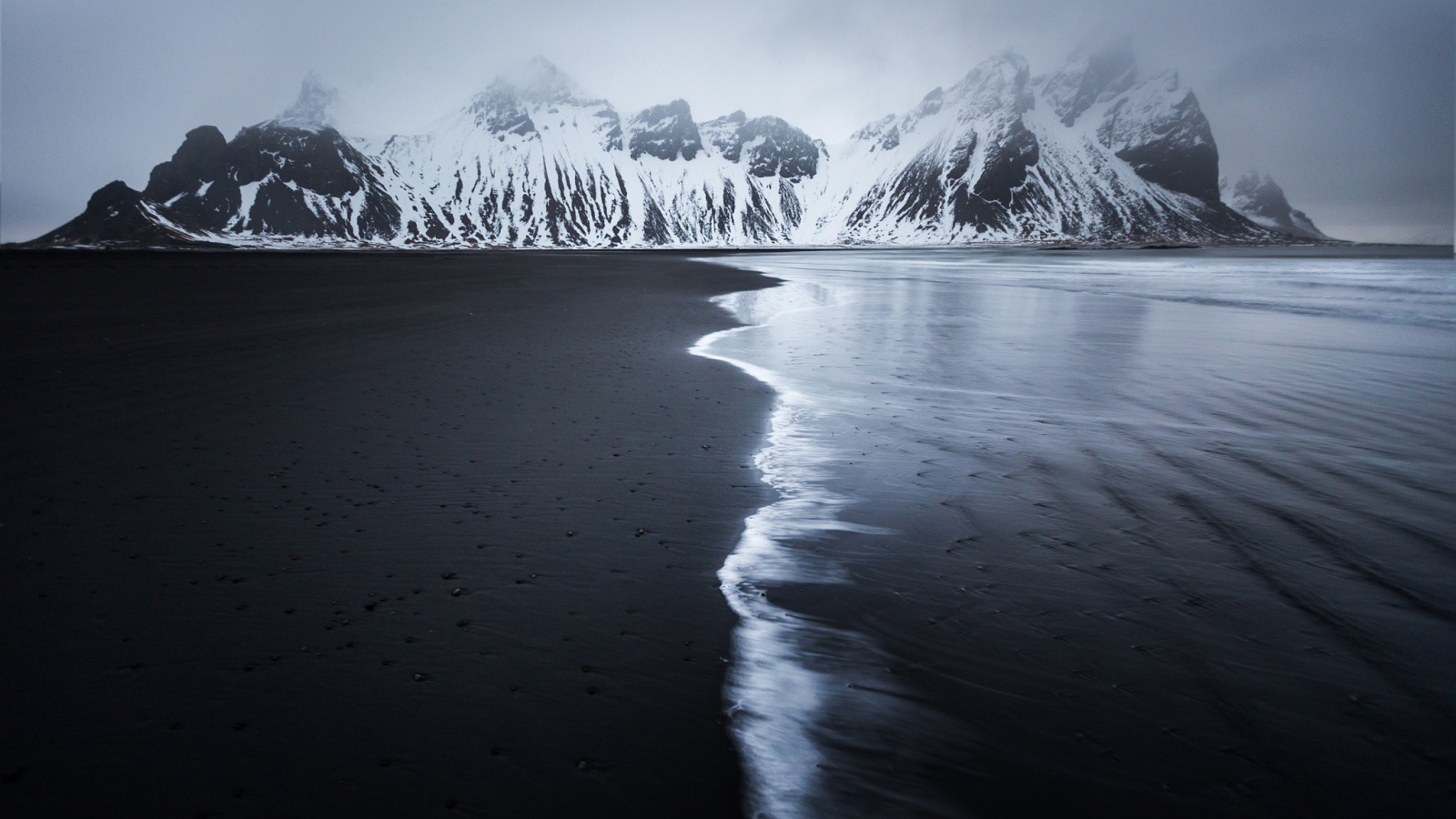 Заснеженные горы у пустынного пляжа