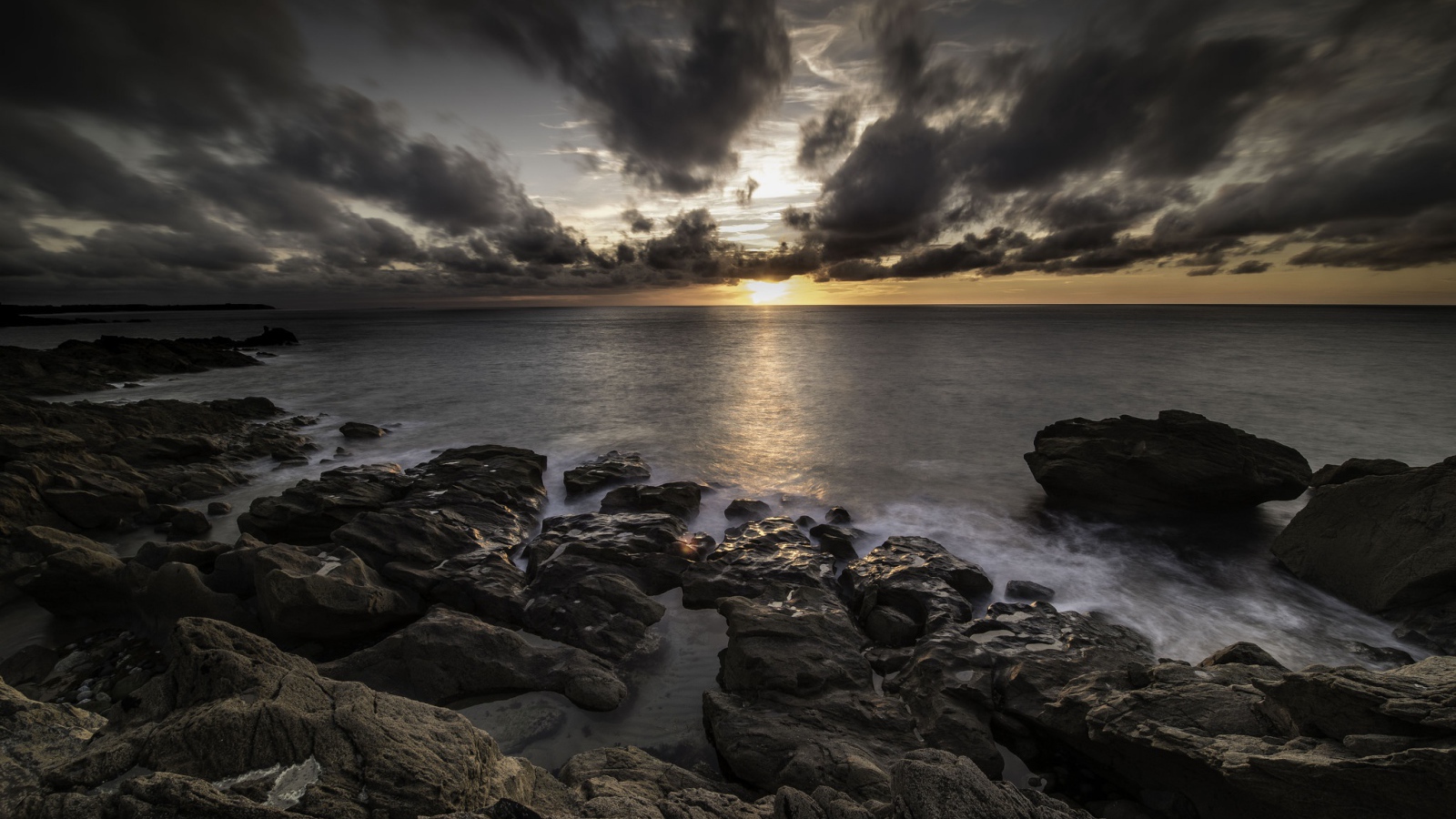 Низкие черные облака на закате в небе над океаном