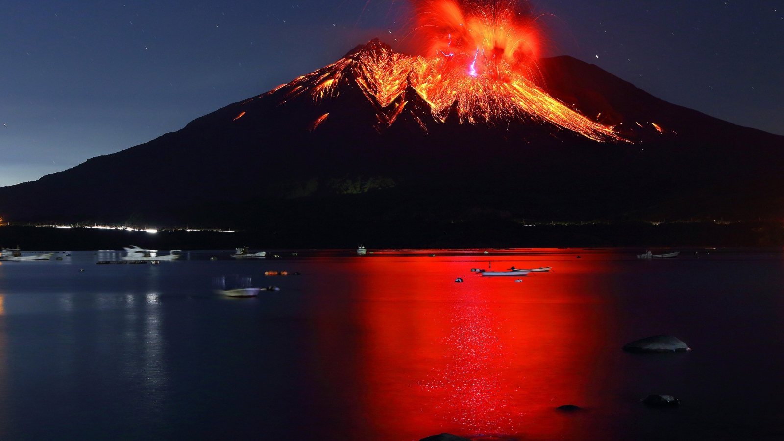 Вулкан Сакурадзима извергается  на фоне воды 