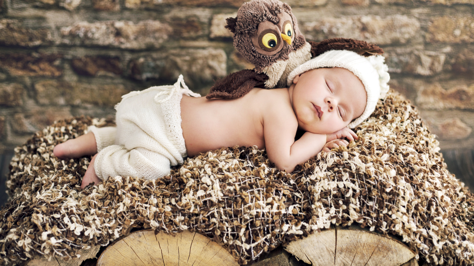 Грудной ребенок спит рядом с игрушкой совой