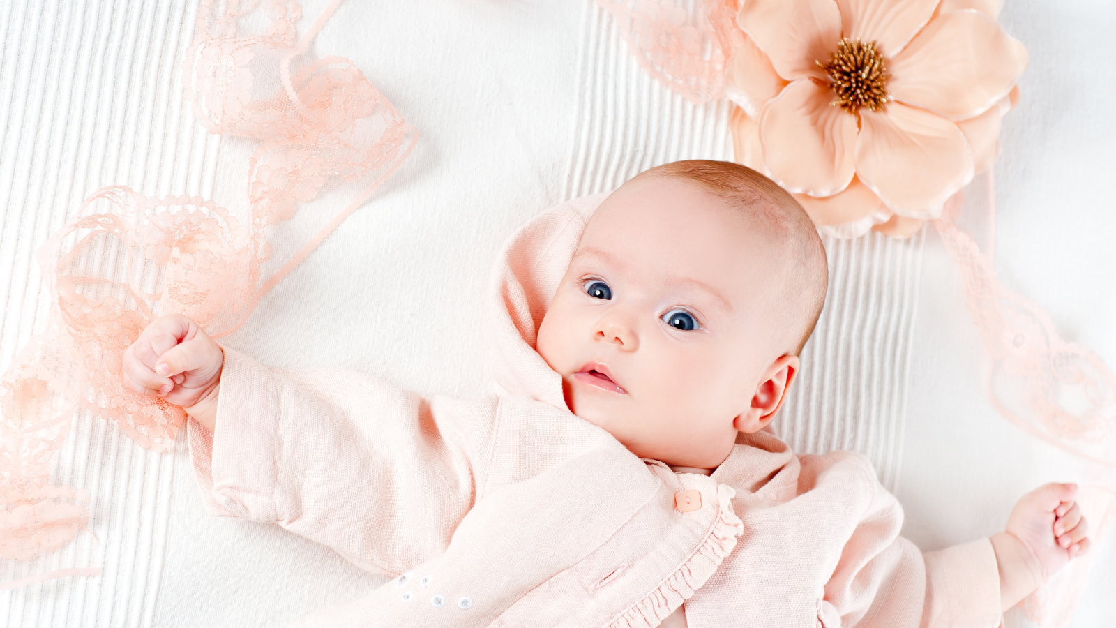 Младенец в розовом наряде с большим цветком у головы